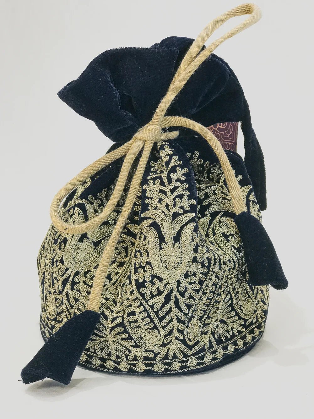 Black and gold patterned drawstring bag with tassels on a white background