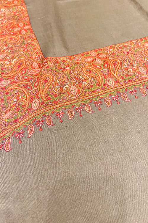Textile with intricate orange and green paisley pattern on a beige background