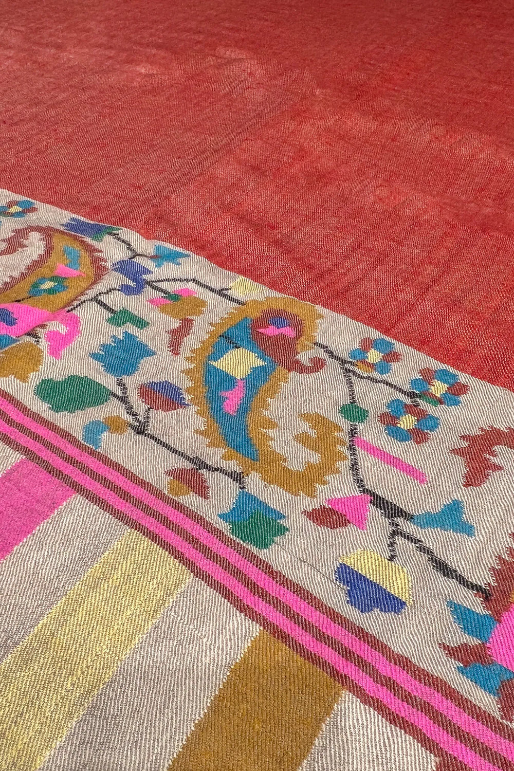 Textile with intricate patterns and colors on a red background