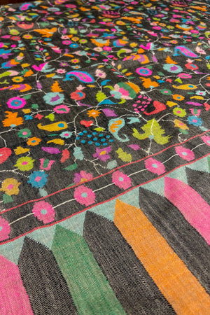 Colorful patterned shawl with geometric shapes and floral designs on a dark background