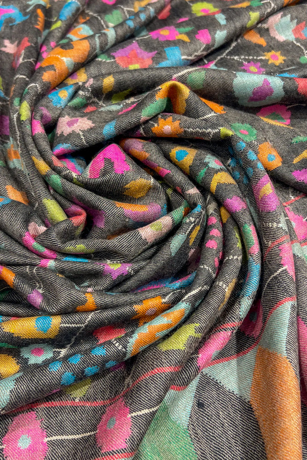 Colorful fabric with a pattern of flowers and abstract shapes on a dark background