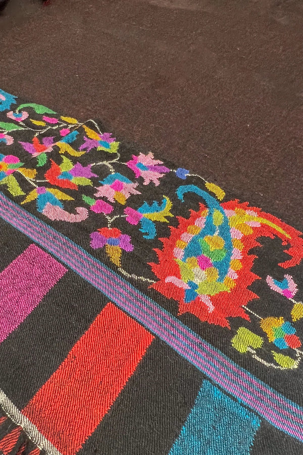 Colorful embroidered fabric with intricate patterns on a dark background