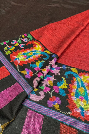 Colorful embroidered fabric with intricate patterns on a black background
