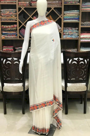 #White saree with colorful border on a mannequin in a store setting