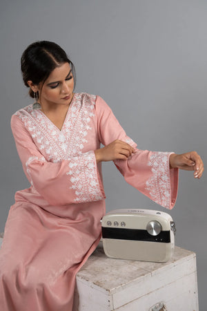 #BlushPink Woman in a pink traditional outfit sitting next to a vintage radio on a gray background
