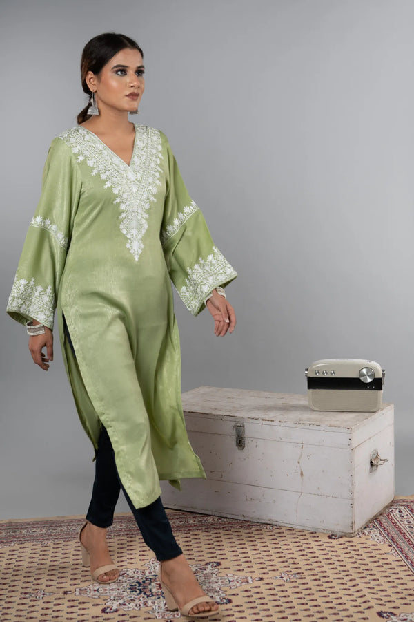 #MossGreen Woman wearing a green embroidered kurta with a white chest in the background
