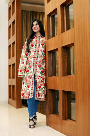 Woman wearing a floral dress standing in front of a wooden door.