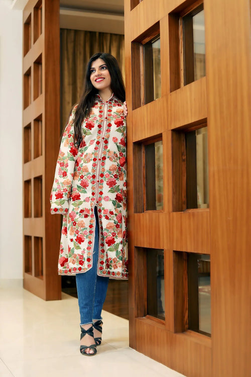 Woman wearing a floral dress standing in front of a wooden door.