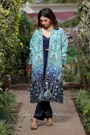 #OmbreBlue&Green Woman wearing a teal and blue patterned coat in a garden setting