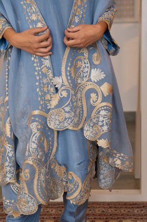 Close-up of organza dupatta pallu showing large-scale gold and silver zari paisley and floral vine embroidery with scalloped edge.