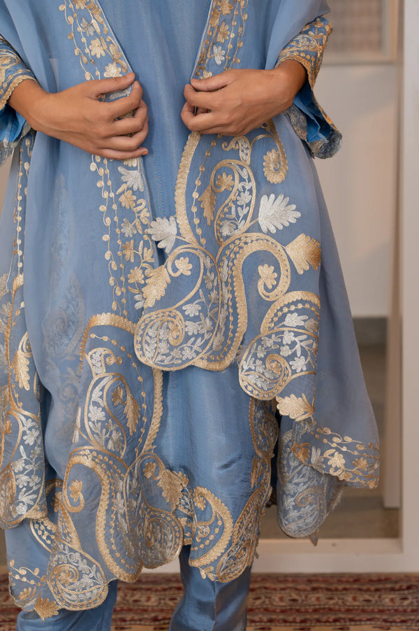 Close-up of organza dupatta pallu showing large-scale gold and silver zari paisley and floral vine embroidery with scalloped edge.