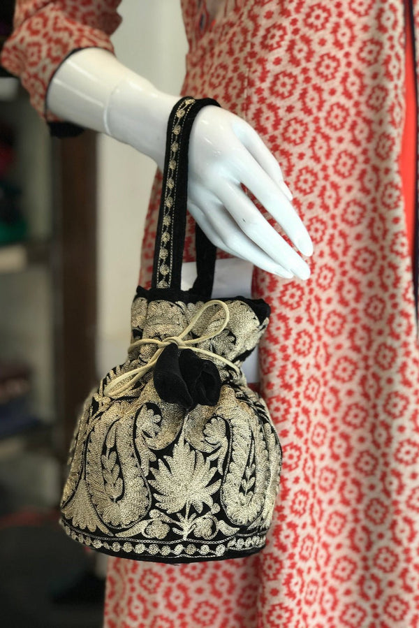 #black Decorative handbag with intricate patterns on a mannequin against a patterned fabric background