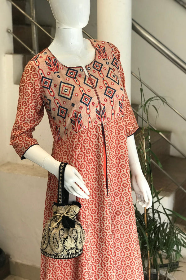 #black Mannequin wearing a red patterned dress with a matching handbag indoors.