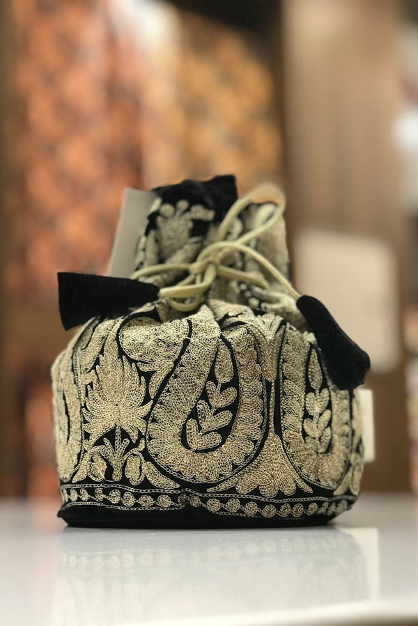 #Black Decorative bag with intricate patterns on a reflective surface