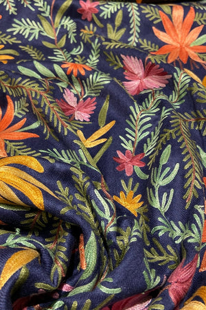 Embroidered fabric with colorful floral and leaf patterns on a dark blue background