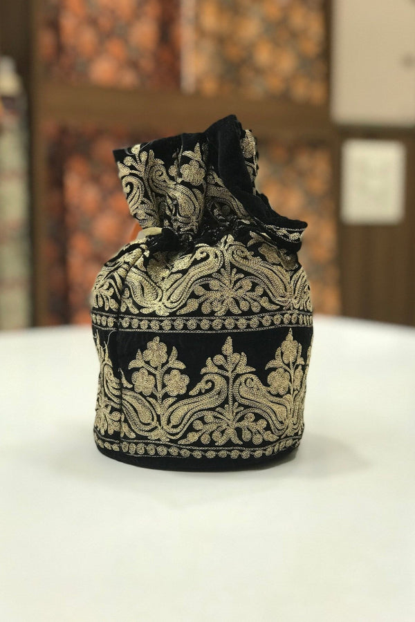 #black Decorative black and gold potli on a white surface with a blurred background