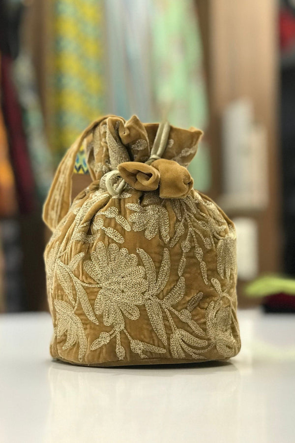 #Gold Decorative fabric pouch with floral embroidery on a blurred background