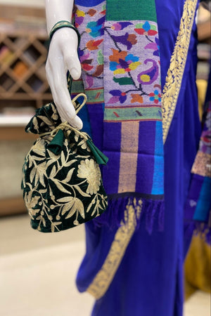 #BottleGreen Mannequin hand holding a black floral bag with a colorful background