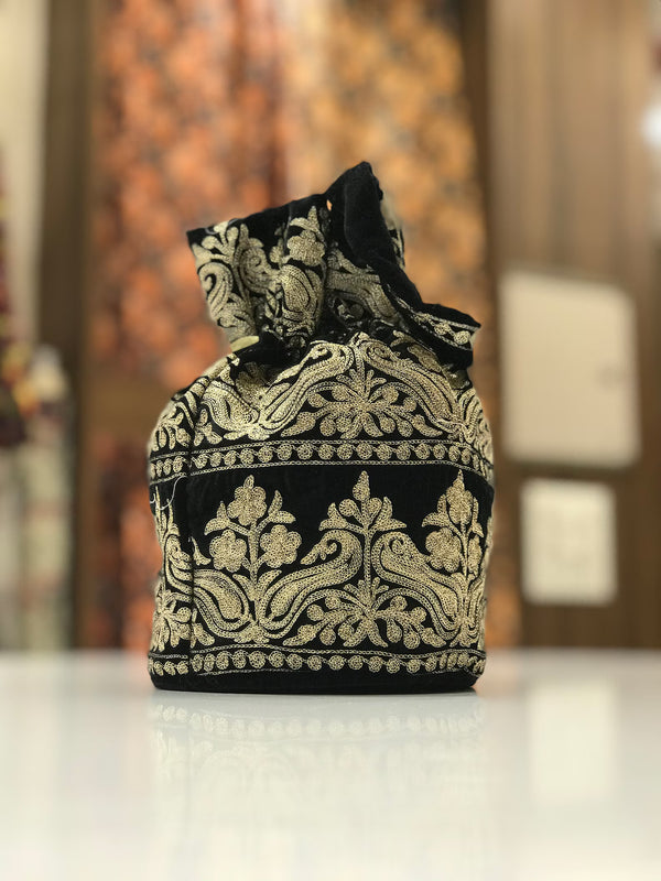 #black Decorative black and gold embroidered bag on a white surface with a blurred background