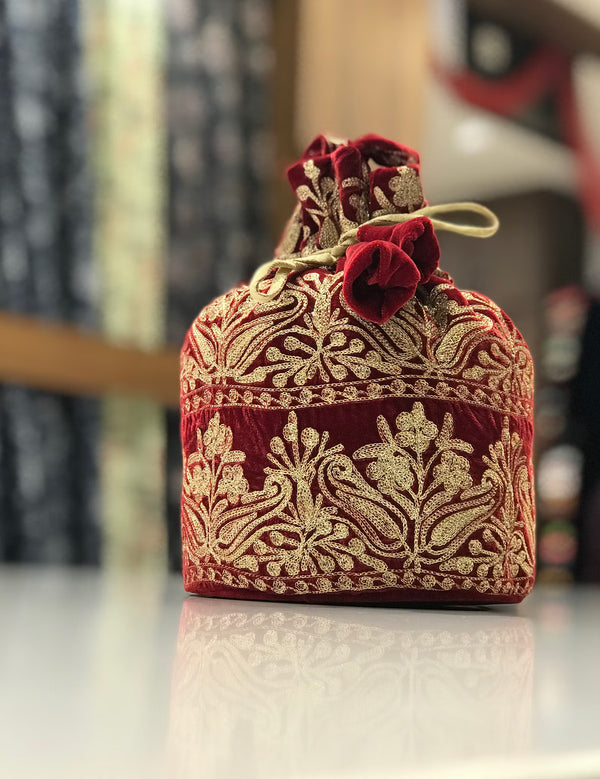 #Red Decorative red and gold embroidered bag on a reflective surface with a blurred background