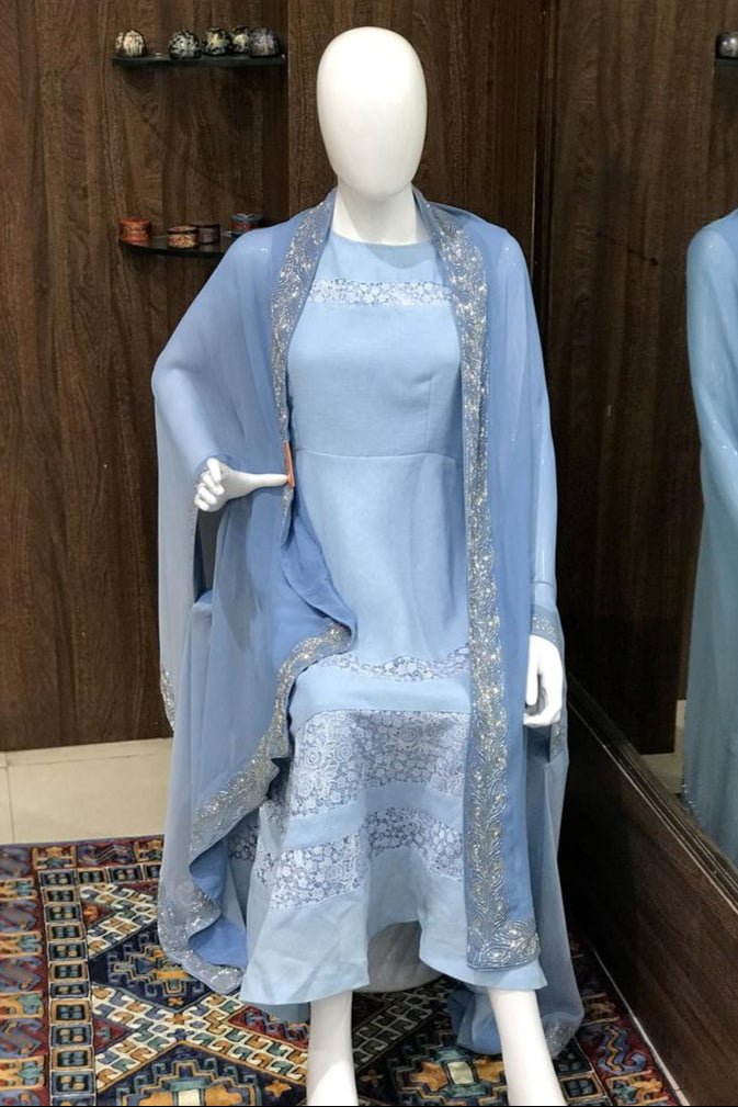 Mannequin wearing a light blue dress with a matching shawl in front of a mirror.