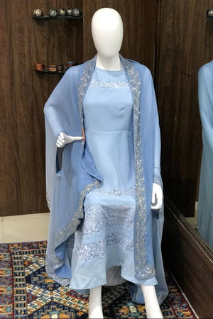 Mannequin wearing a light blue dress with a matching shawl in front of a mirror.