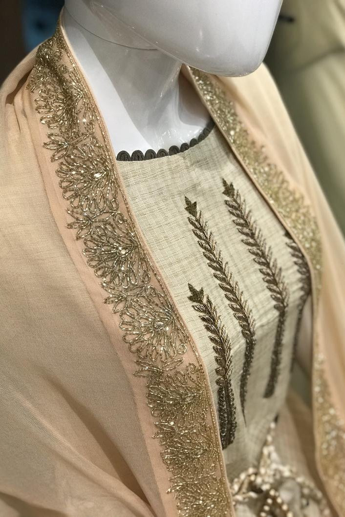 Beige embroidered garment on a mannequin with a blurred background