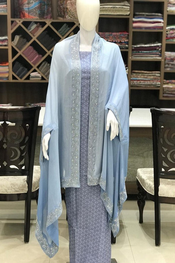 Mannequin wearing a light blue cape in a store setting.