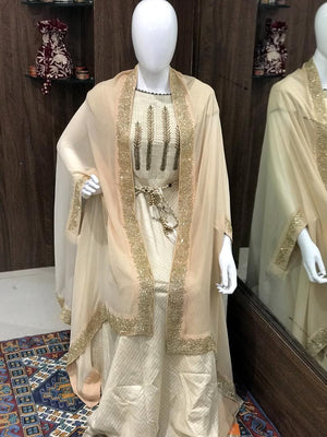 Mannequin wearing a beige dress with gold embroidery in a store setting.