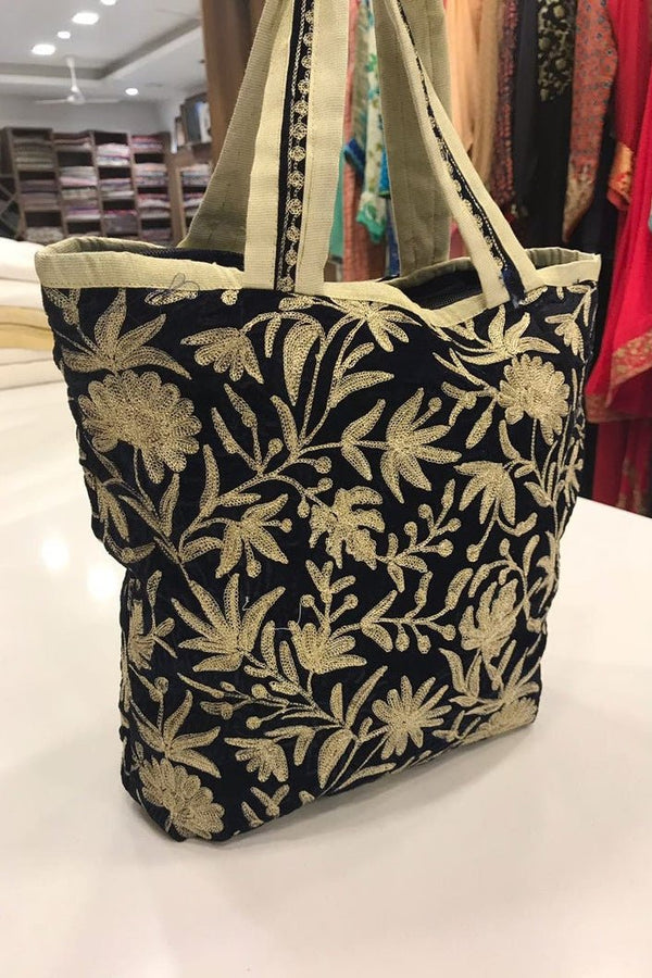 Black tote bag with gold floral pattern on a white surface
