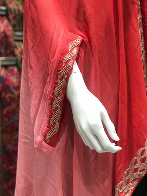 Red garment with gold embroidery on a mannequin arm against a colorful background