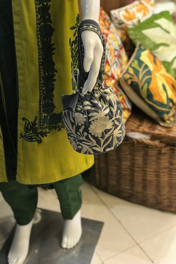 #Gray Mannequin wearing a green outfit with a floral-patterned bag, surrounded by colorful pillows.
