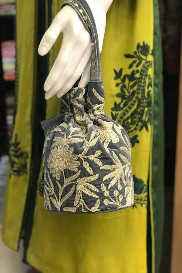 #Gray Decorative bag with floral patterns on a mannequin hand against a green fabric background