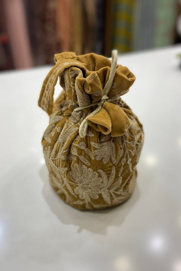 #Gold velvet drawstring bag with floral patterns on a white surface