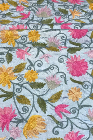 Embroidered fabric with colorful floral pattern on a light blue background