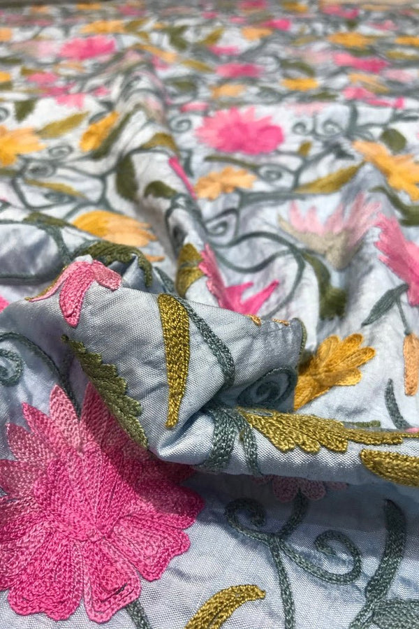 Close-up of embroidered fabric with floral patterns on a gray background