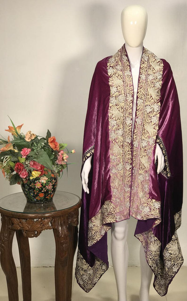 Mannequin wearing a patterned purple scarf with a vase of flowers on a table in the background.