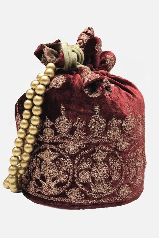 Decorative red potli bag with gold embroidery and a string of pearls on a white background