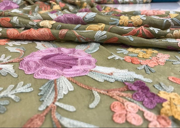 Close-up of embroidered fabric with floral patterns on a green background