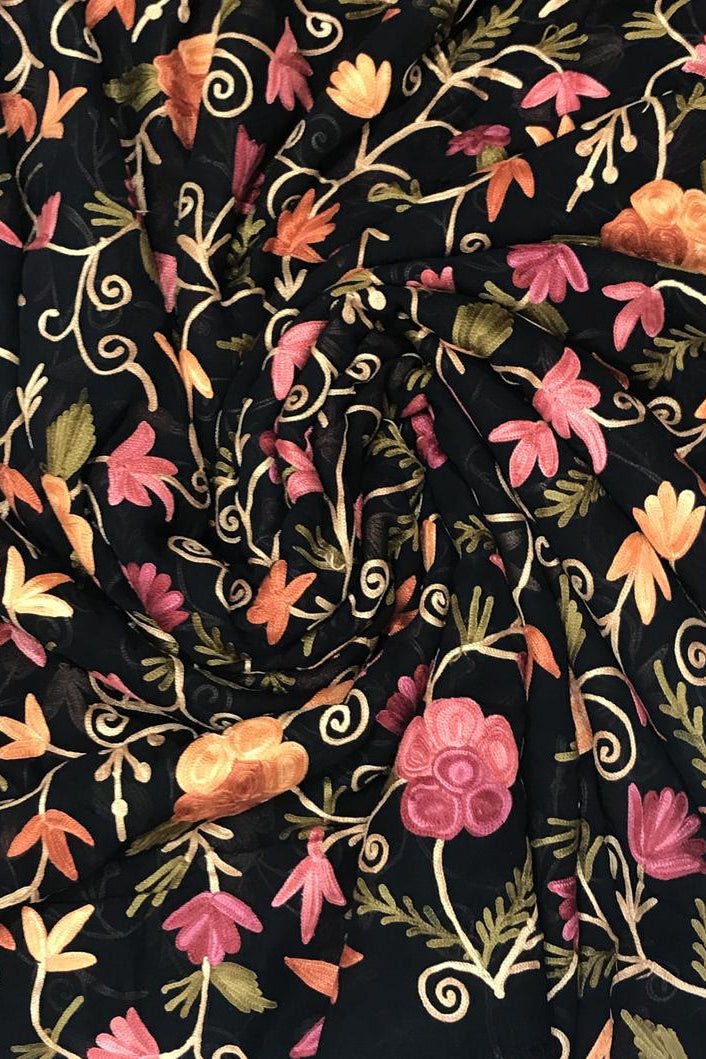 Floral embroidery pattern on black fabric with pink, orange, and green flowers.