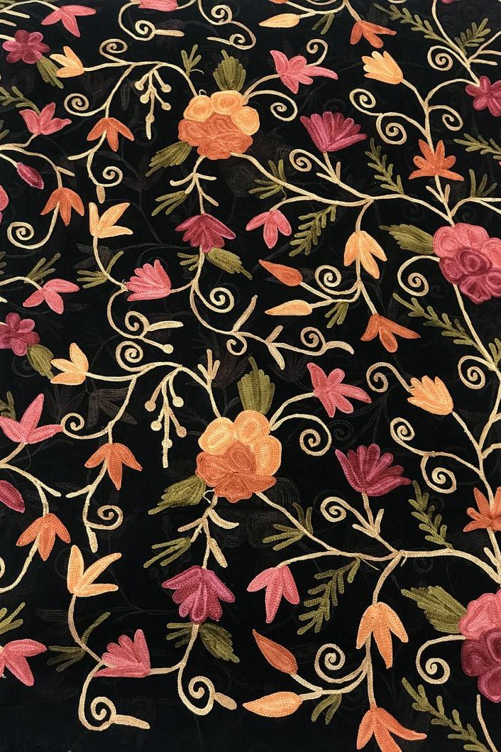 Floral embroidery pattern on black fabric with pink, orange, and green flowers.