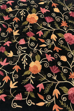 Floral embroidery pattern on black fabric with pink, orange, and green flowers.