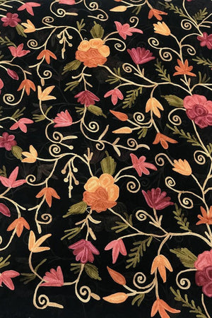 Floral embroidery pattern on black fabric with pink, orange, and green flowers.